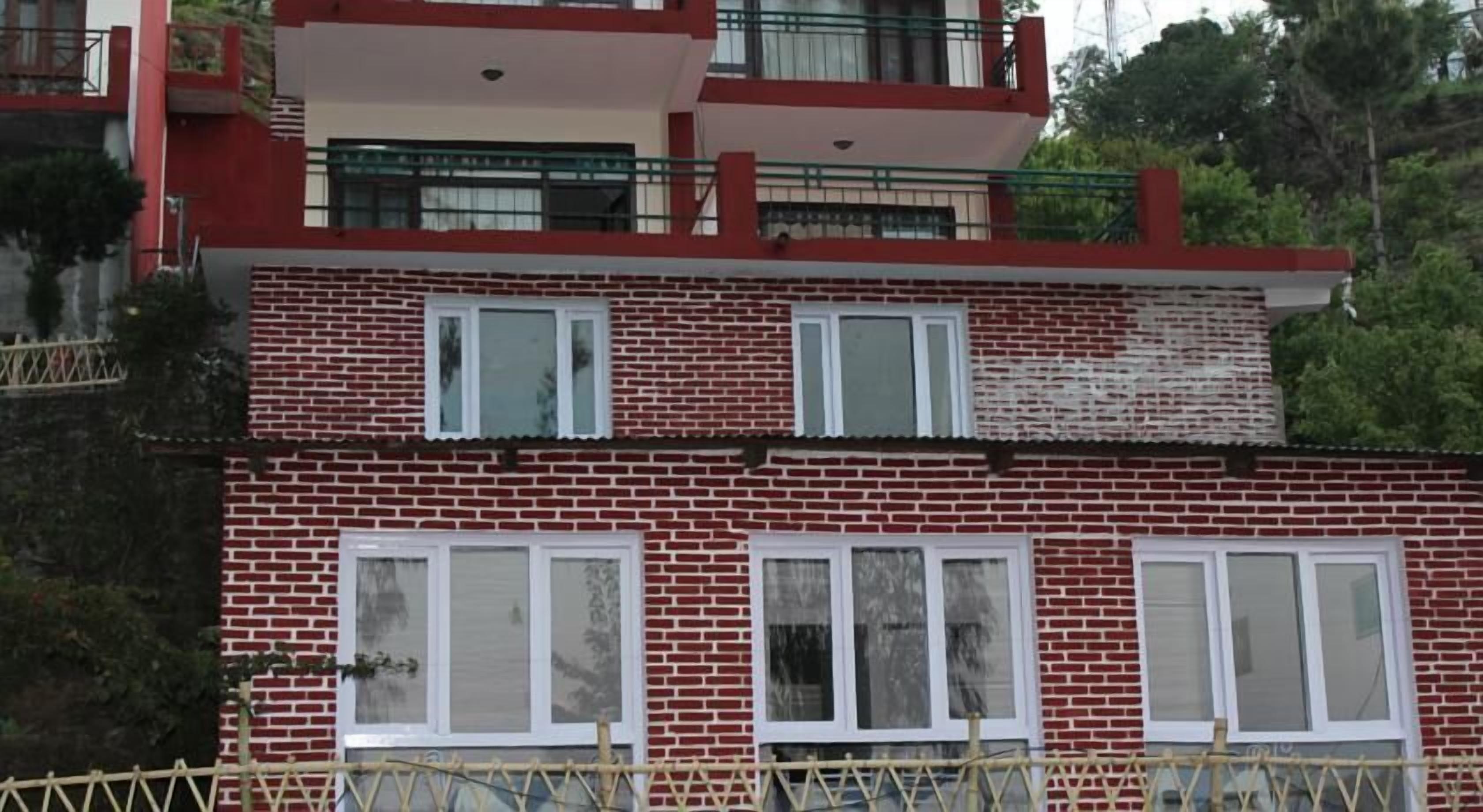 Un edificio de dos pisos con paredes de ladrillo rojo y marcos de ventana blancos.