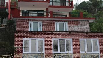 Un edificio de dos pisos con paredes de ladrillo rojo y marcos de ventana blancos.