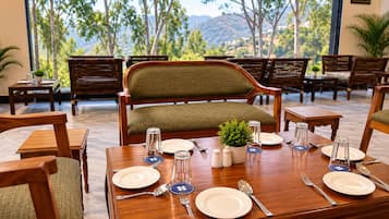 Un comedor con una mesa dispuesta para cuatro personas, rodeada de sillas de madera y un banco acolchado.