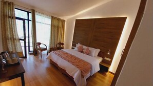 A modern bedroom with a large bed, wooden headboard, and a desk with a chair.