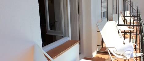 A balcony with white chairs and a wooden ledge.