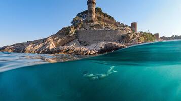 A historic fort with a tower, surrounded by clear blue waters.