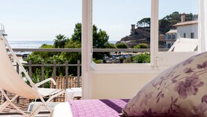 Un balcón con una cama, una silla y vistas al mar y a edificios.