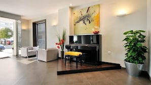Una sala de estar moderna con un piano, un sofá, un banco y un cuadro abstracto grande en la pared.