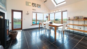 A spacious kitchen with a large dining table, modern appliances, and large windows offering a view of the outdoors. - Great Blasket, Dunquin (Dunquin)