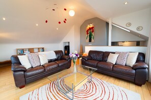 Een moderne woonkamer met twee leren banken, een glazen salontafel en een kamerbreed tapijt met een patroon.