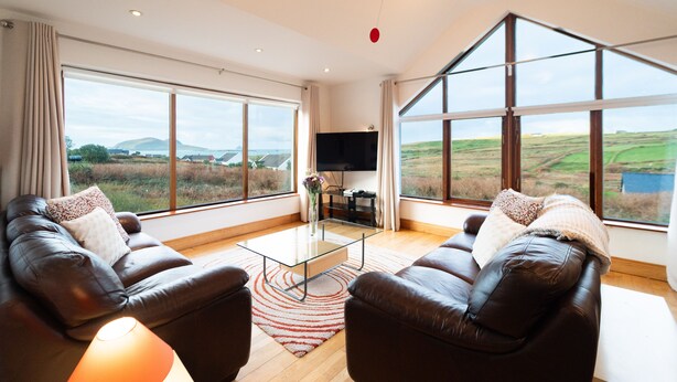 A spacious living room with leather sofas, a glass coffee table, and a large TV. - Great Blasket, Dunquin (Dunquin)