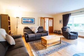 Ein Wohnzimmer mit einer Couch, Sesseln, einem Couchtisch und einem Bücherregal.