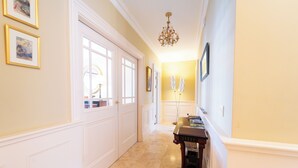 A hallway with white doors, a chandelier, and framed pictures on the walls. - Waters Edge Apartment 2 (Dingle)