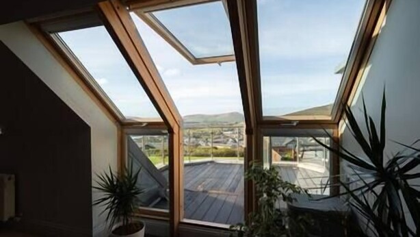 A room with a sloped ceiling and large skylights, providing a view of a cityscape and hills.