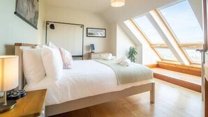 A bedroom with a bed, bedside table, and a skylight.