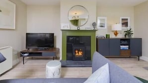 Ein Wohnzimmer mit Kamin, Fernseher, Sofa und Schrank.