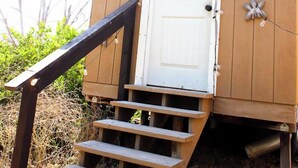 Eine Holzkonstruktion mit einer weißen Tür, einer Holztreppe und dekorativen Wandleuchten.