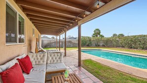 A covered patio with a pool, a cushioned seating area, and a table with a drink. - Arizona Daydream + Private Pool + EV Charger (Chandler)