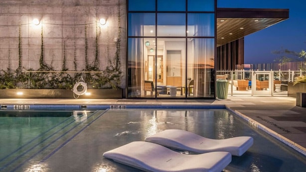 A modern hotel with a swimming pool, lounge chairs, and a well-lit interior. - 2BR + Luxury +Views +Rooftop pool in Austin (Austin)