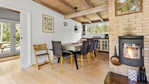 A cozy dining area with a wooden table and chairs, a fireplace, and a view of the outdoors. - 3 bedroom nice home in Melby (Melby)