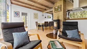A cozy living room with a fireplace, wooden furniture, and a dining area with a table and chairs. - 3 bedroom nice home in Melby (Melby)