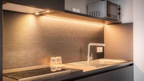 A modern kitchen with a built-in microwave, a stainless steel sink, and a sleek countertop. - Hotel Jamingo (Antwerp)