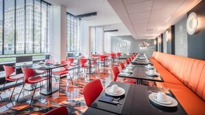 A modern dining area with red chairs, black tables, and orange seating. - Hotel Jamingo (Antwerp)