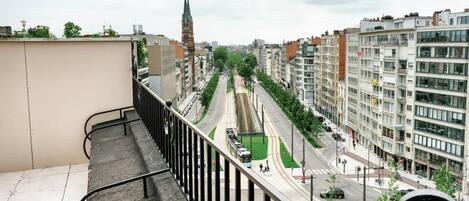 Una calle de la ciudad con un tranvía, edificios y la aguja de una iglesia a lo lejos.