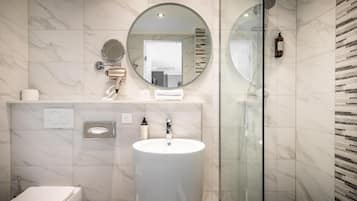 Une salle de bain moderne avec un grand miroir rond, un lavabo et une douche à parois de verre.
