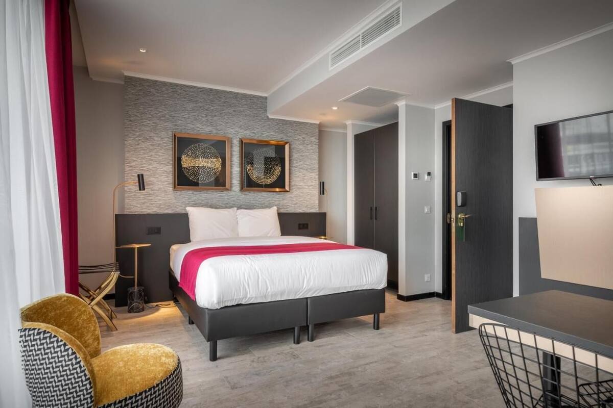 A modern hotel room with a large bed, a desk, and a television.