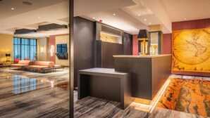 A modern hotel lobby with a reception desk, seating area, and large windows. - Hotel Jamingo (Antwerp)