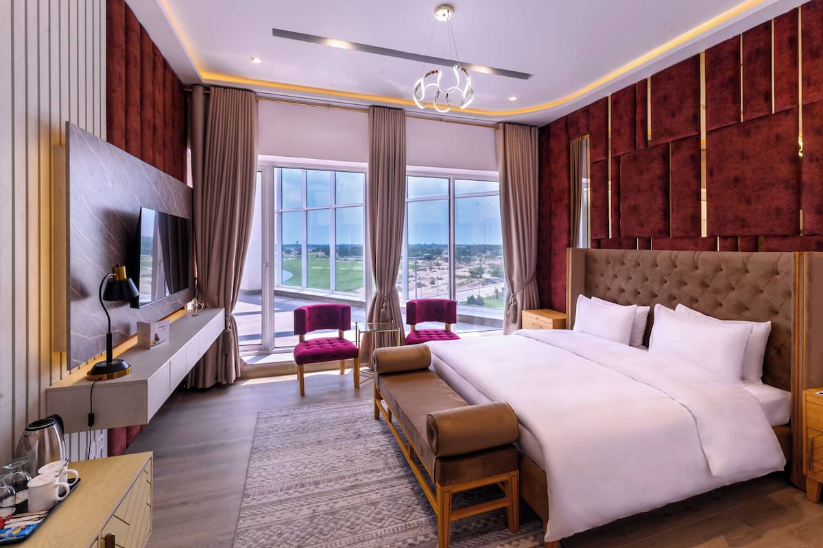 Habitación de hotel moderna con una cama grande, televisor, escritorio y vistas a la ciudad.