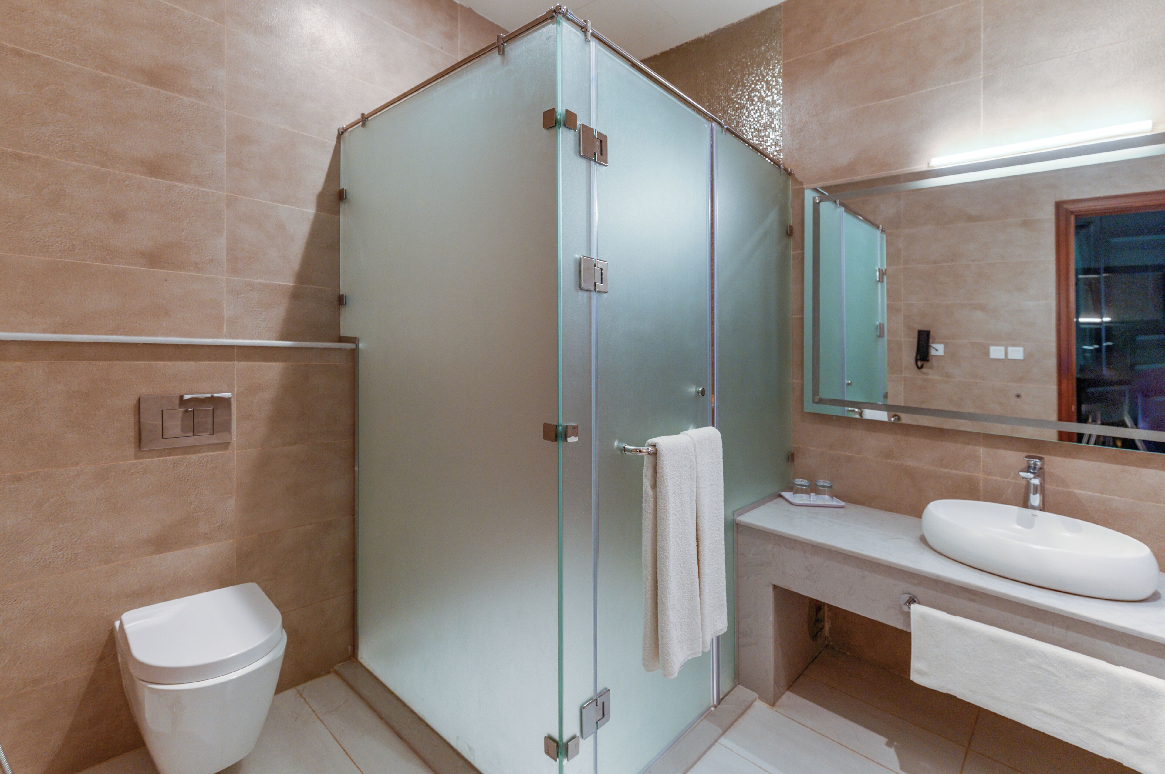 A bathroom with a glass-enclosed shower, a white sink, and a mirror above the sink.