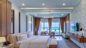 A spacious bedroom with a large bed, a desk, and a TV. - Rumanza by Pearl Continental (Multan)