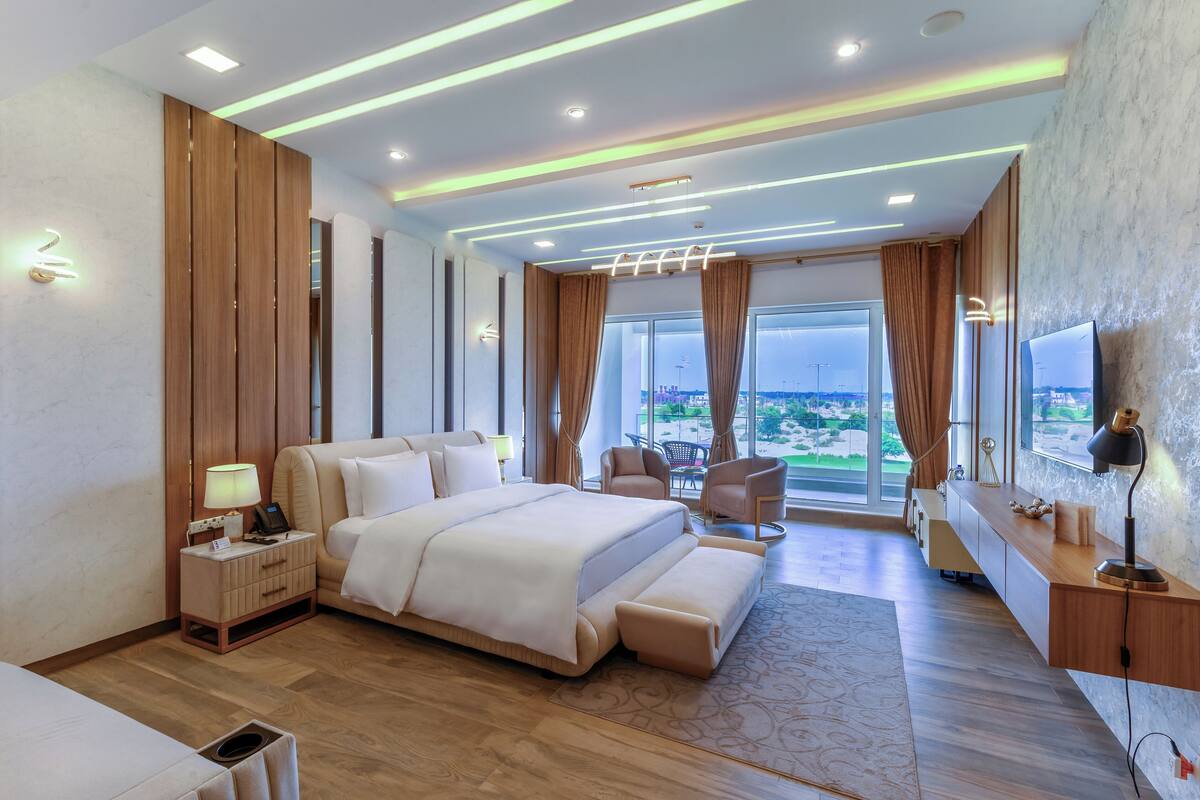 Habitación de hotel moderna con una cama grande, un escritorio, una silla y vistas a la ciudad.