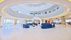 A spacious, multi-level atrium with a central circular design, featuring blue seating areas and a distinctive white sculpture. - Rumanza by Pearl Continental (Multan)
