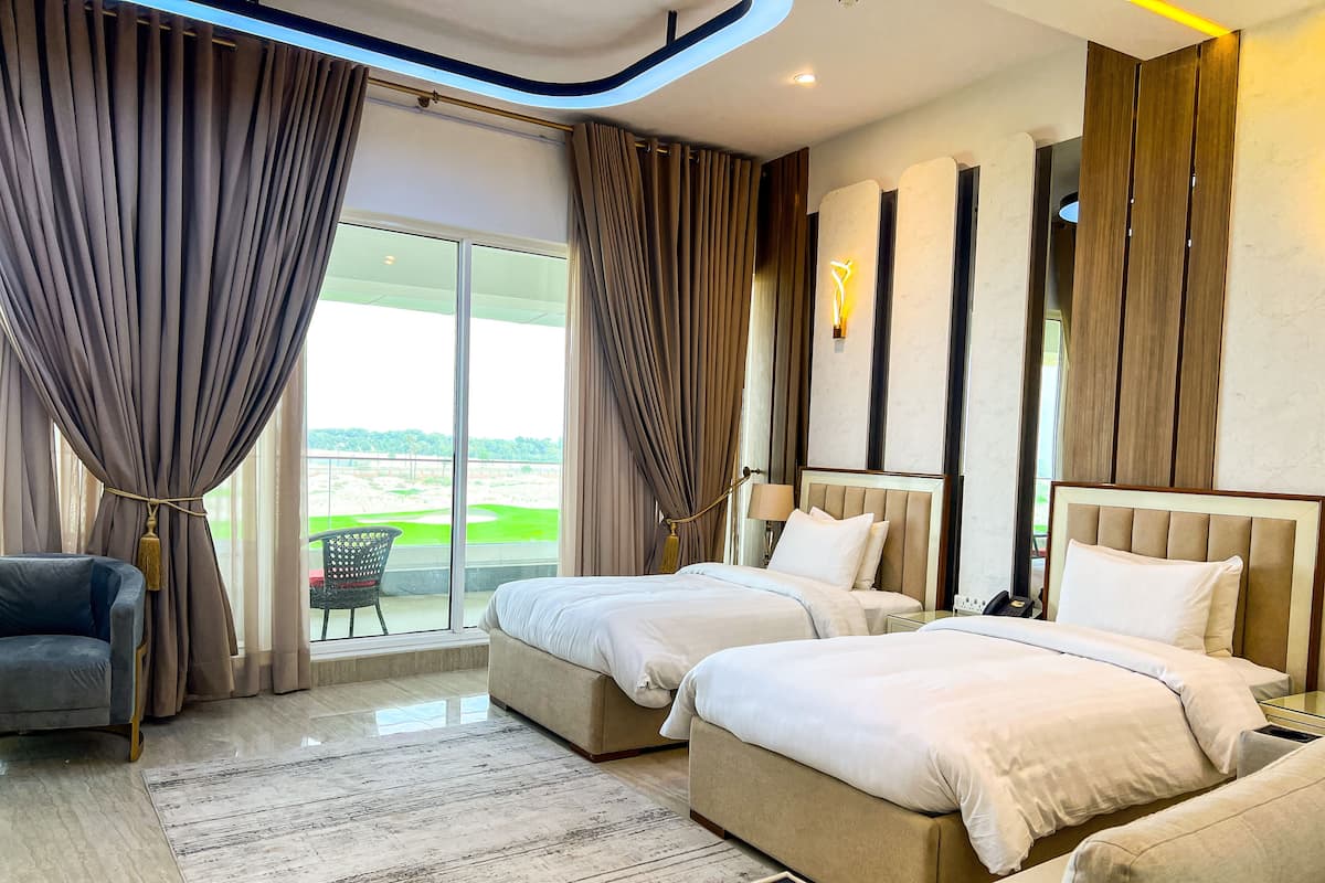 Habitación de hotel con dos camas, un sofá, una silla y vista a un campo de golf.
