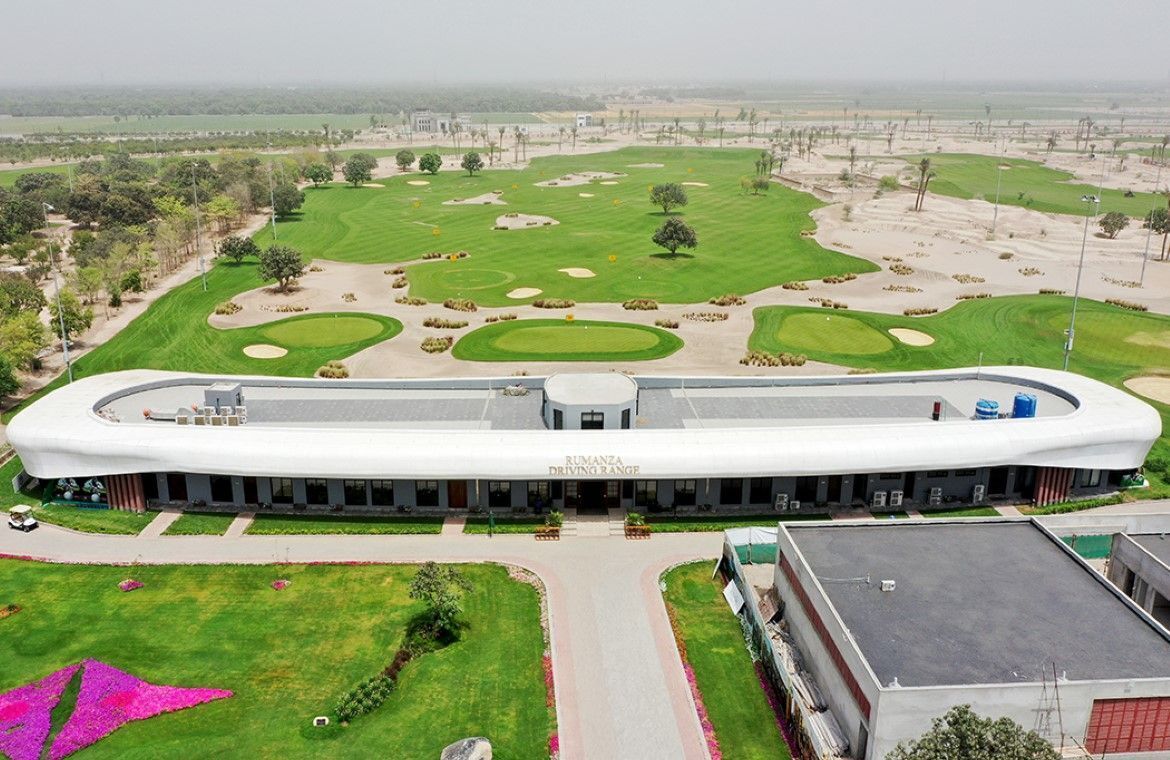A modern building with a curved roof and a sign reading "RUMANZA DRIVING RANGE".