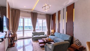 A modern hotel room with a sofa, a coffee table, and a TV. - Rumanza by Pearl Continental (Multan)