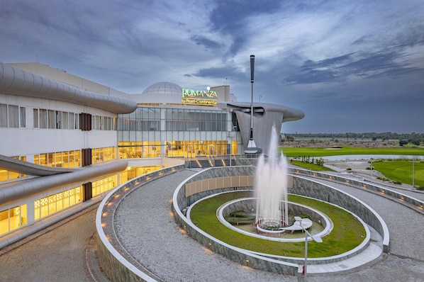 A modern building with a large fountain in the center, surrounded by a circular pathway.