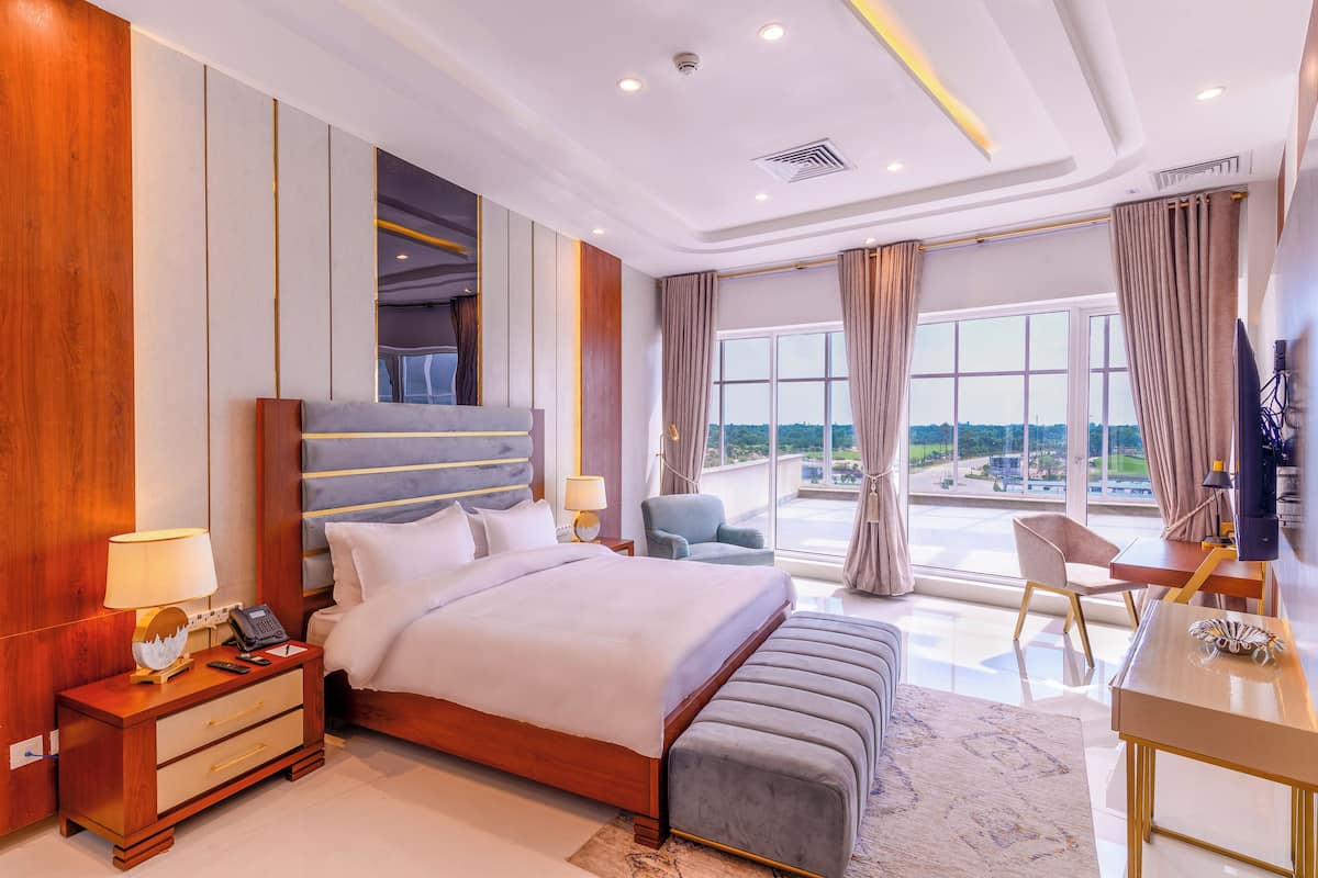 Habitación de hotel moderna con una cama grande, un escritorio, una silla y vistas a la ciudad.
