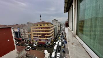 A busy urban street with a multi-story building featuring a prominent antenna.