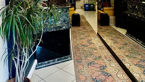 A hotel lobby with a tiled floor, a large mirror, a staircase, and a potted plant. - Hotel Nayla (Istanbul)