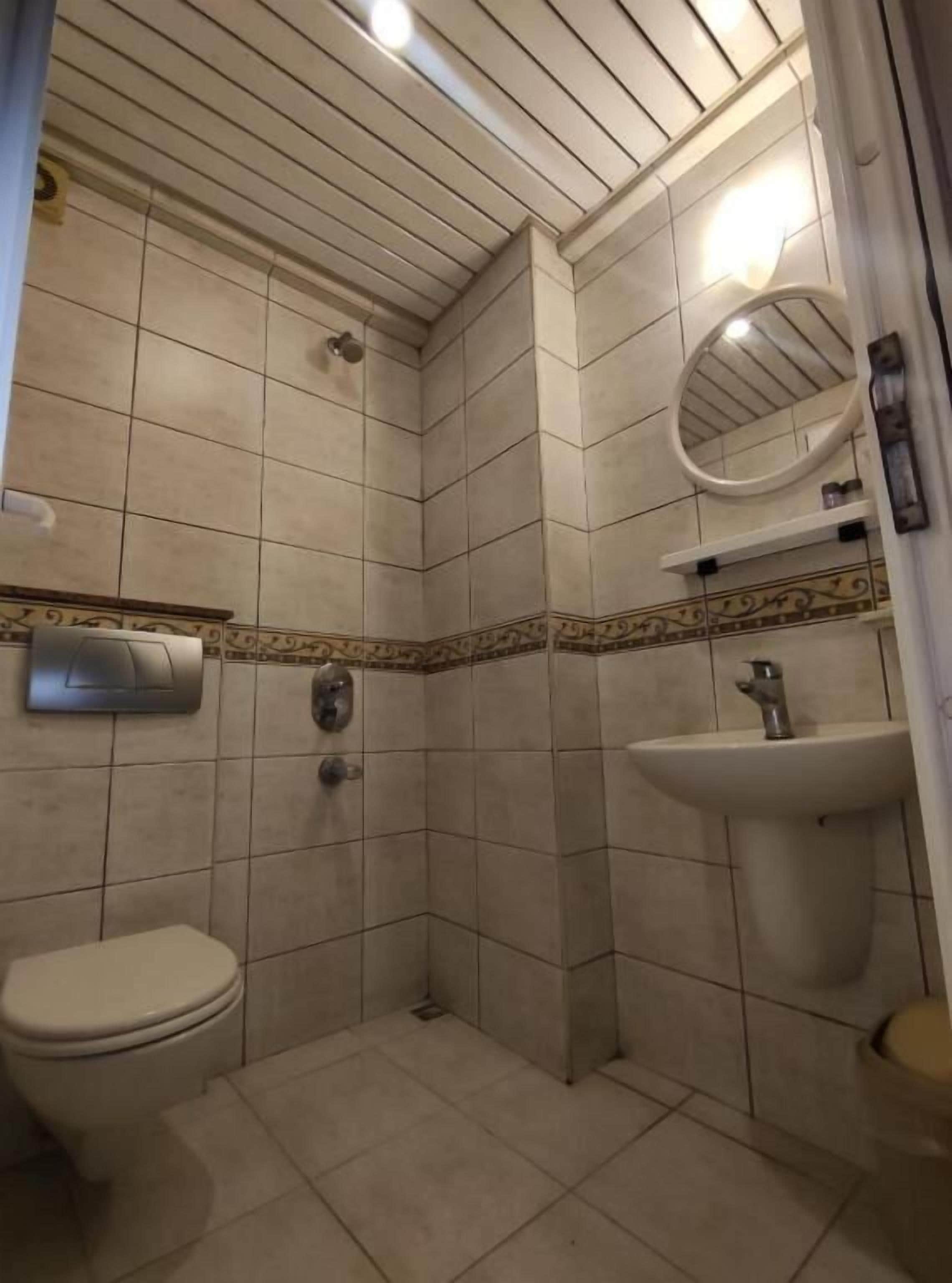 Et badeværelse med toilet, bruser og vask.
