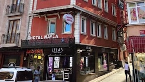 A multi-story hotel with a red facade, balconies, and storefronts including 'Hotel Nayla' and 'Lelas'. - Hotel Nayla (Istanbul)