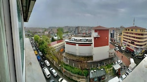 A cityscape with a prominent building featuring a red and white facade, surrounded by parked cars and a busy street. - Hotel Nayla (Istanbul)