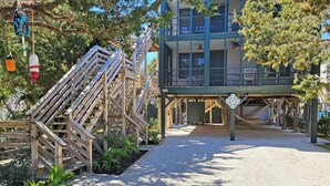 A wooden staircase leading to a covered area with a sign reading "The Booy." - Charming Second Row Beach House - 1st Floor Only, 2 Screened Porches, Grill (Pawleys Island)