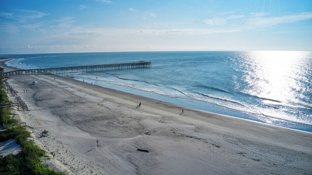A beach with a pier extending into the ocean, sandy beach, and clear blue sky. - Charming Second Row Beach House - 1st Floor Only, 2 Screened Porches, Grill (Pawleys Island)