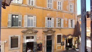 A building with multiple windows, some with shutters, and a sign that reads "CARLO CECCHIN OFFICINE ROMANE." - 4bnb - Lungaretta Jacuzzi Apartment (Rome)