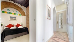 A hotel room with a bed, red pillows, a framed picture, a tiled floor, and a doorway leading to another room. - 4bnb - Lungaretta Jacuzzi Apartment (Rome)