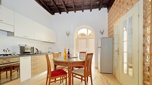 A modern kitchen with white cabinets, a dining table with chairs, and a refrigerator. - 4bnb - Lungaretta Jacuzzi Apartment (Rome)