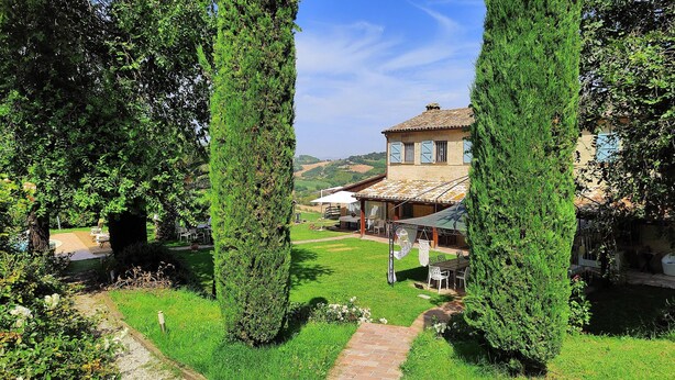A house with a patio area, surrounded by lush greenery and a clear sky. - 3849 Villa Daya by Barbarhouse (Fano)
