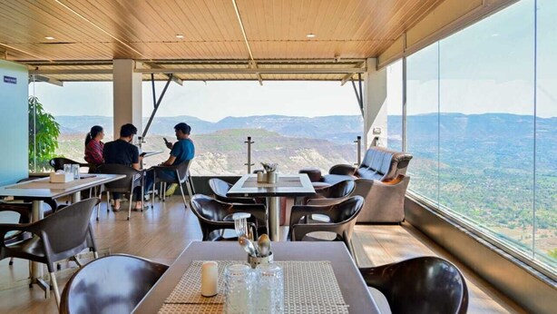 A restaurant with a high ceiling and large windows offering a panoramic view of the landscape. - The Royal Heaven by Joy Suites (Wai)