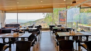 A restaurant with a view of a mountainous landscape. Tables and chairs are arranged for dining. - The Royal Heaven by Joy Suites (Wai)